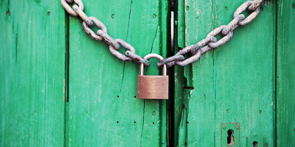 green wooden door with a chain and padlock holding it shut